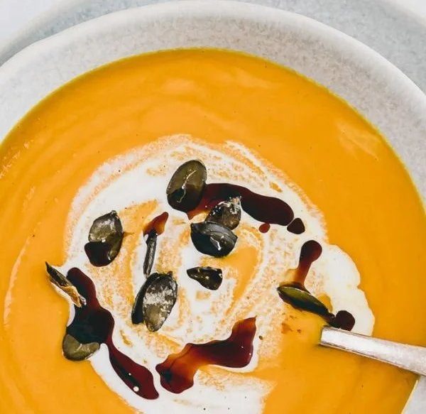 Kürbis Ingwer Suppe in einer Schüssel mit frischen Kräutern garniert