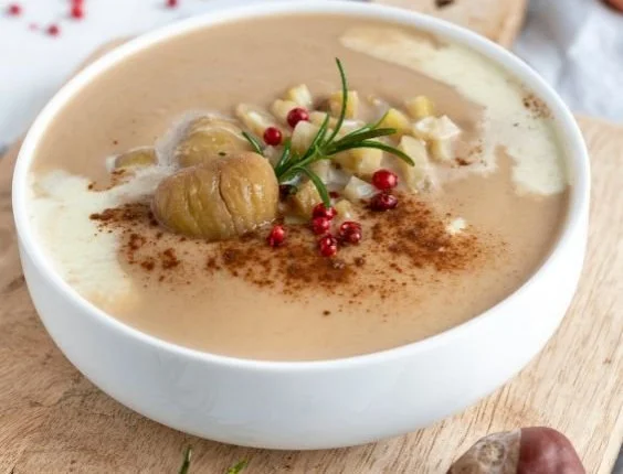 Schüssel mit Maronen Zimt Suppe, serviert mit Zimtstangen und frischen Maronen.