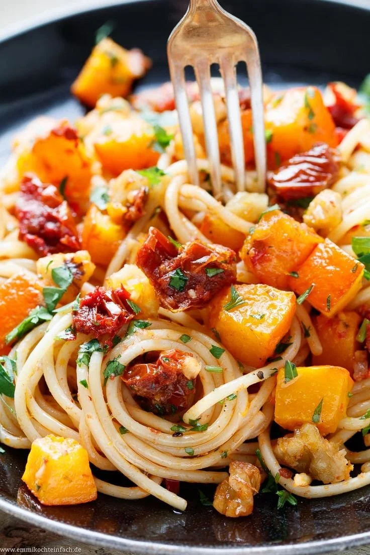 Delicious Pasta mit Kürbis served in a bowl, garnished with herbs.
