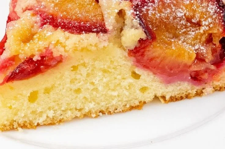 Saftiger Pflaumenkuchen mit Schmand auf einem Teller serviert.