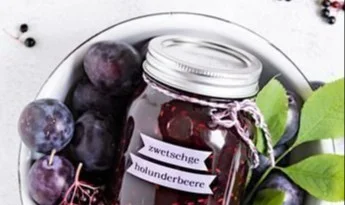 Zwetschgen Holunder Konfitüre mit Vanille in einem Glas auf einem Holztisch